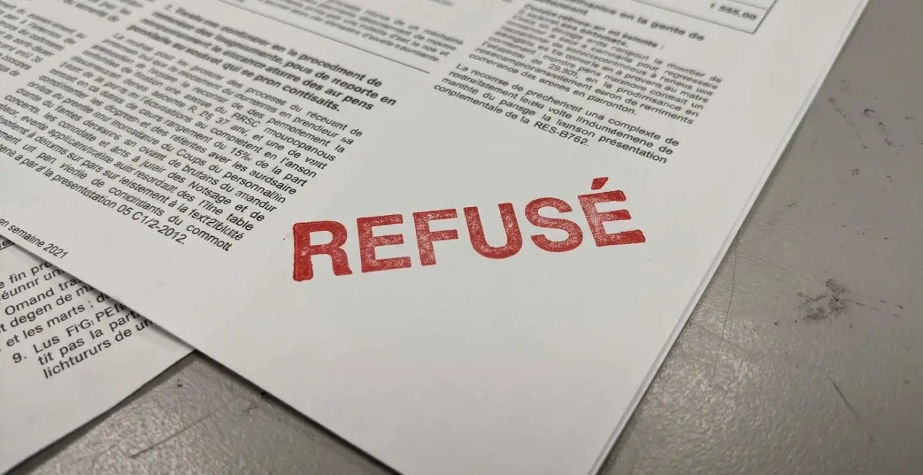 Gros plan rapproché sur un tampon rouge portant la mention REFUSÉ apposé sur un formulaire de demande de prêt immobilier avec fond flouté